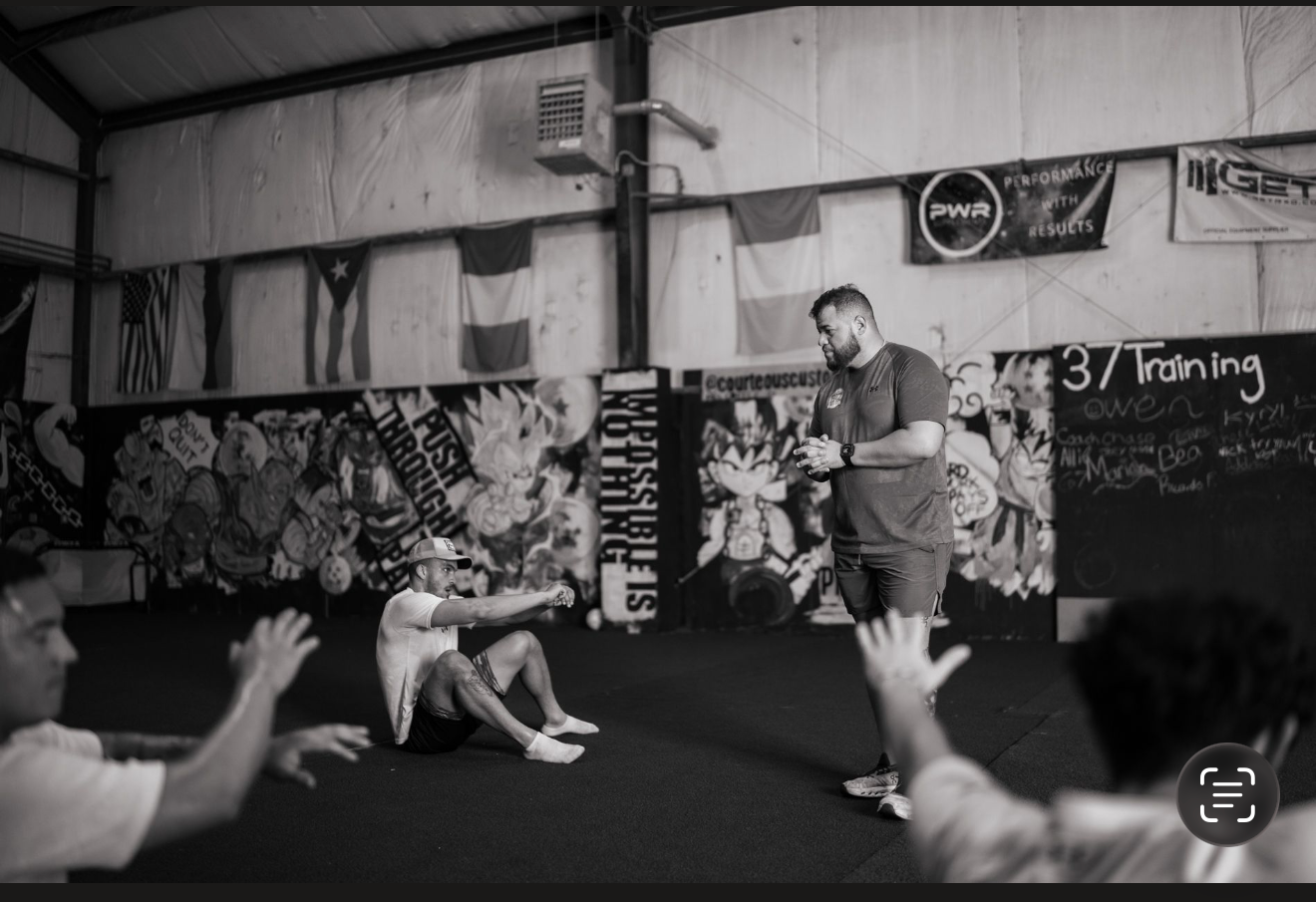 Athletes stretching on the floor while a coach leads the session at The Pack