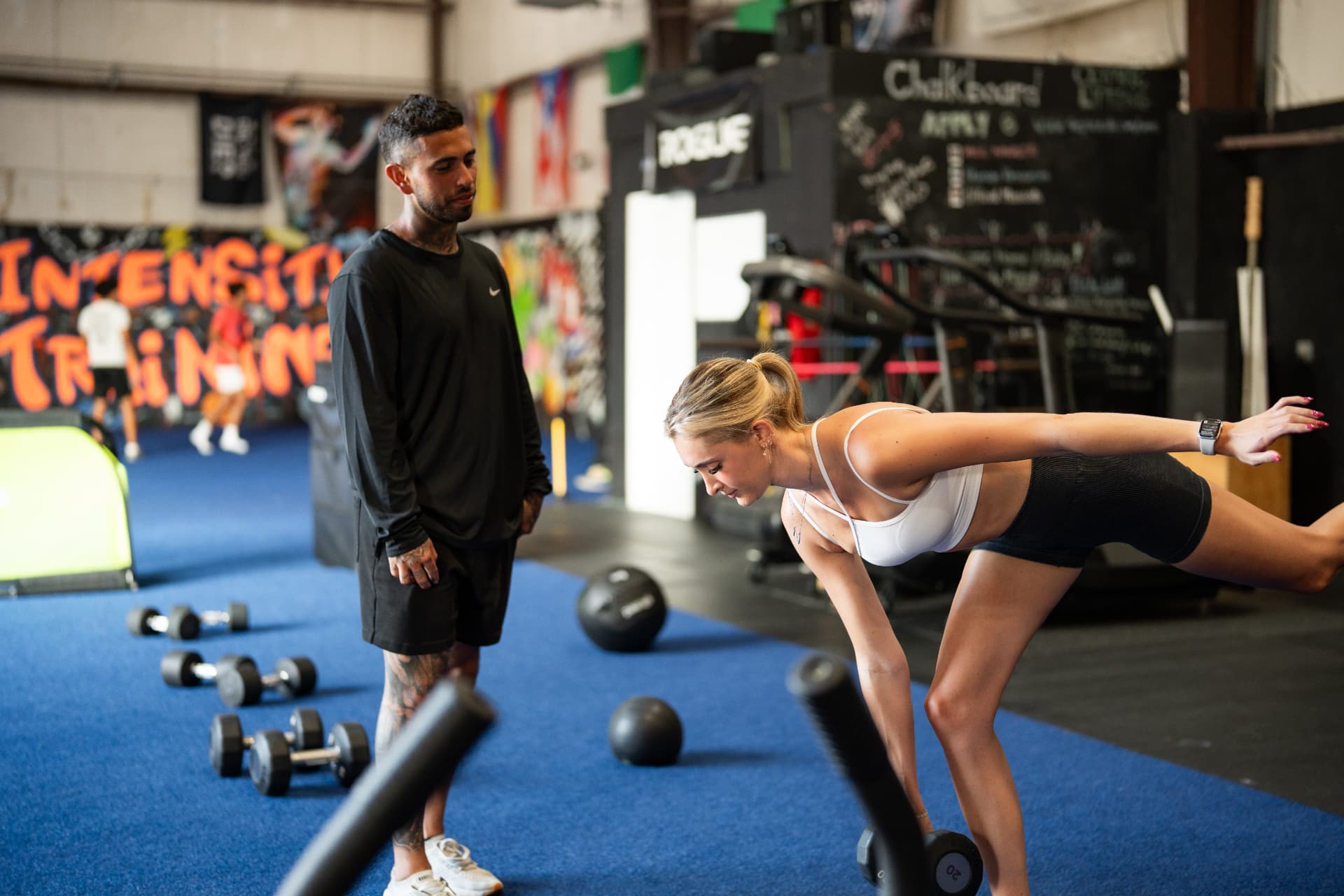 Coach guiding an athlete through a single-leg dumbbell drill at The Pack